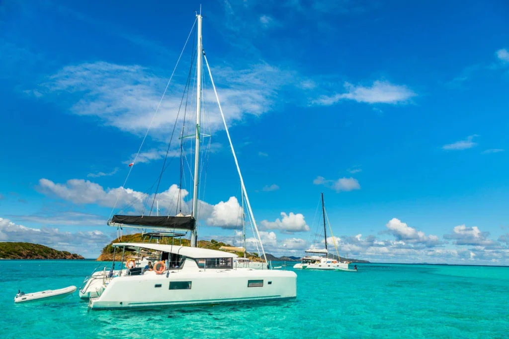 Two Sailboats Anchored in Turquoise Caribbean Water Under a Bright Blue Sky with a Distant Island