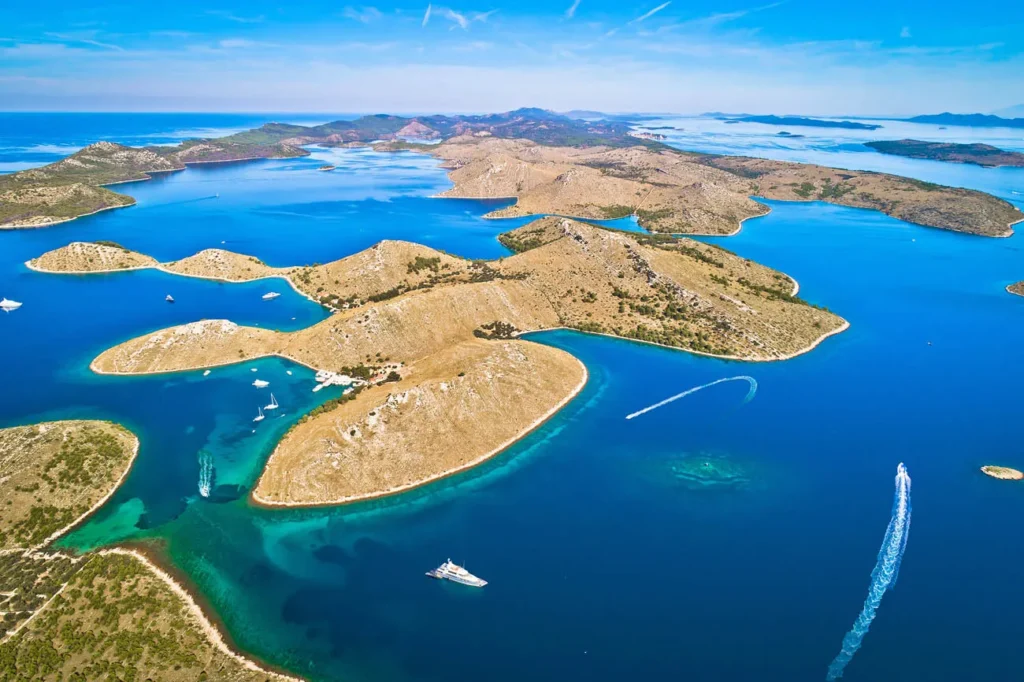Aerial View of Blue Sea with Brown Barren Islands and Several Boats Anchored or Cruising Nearby