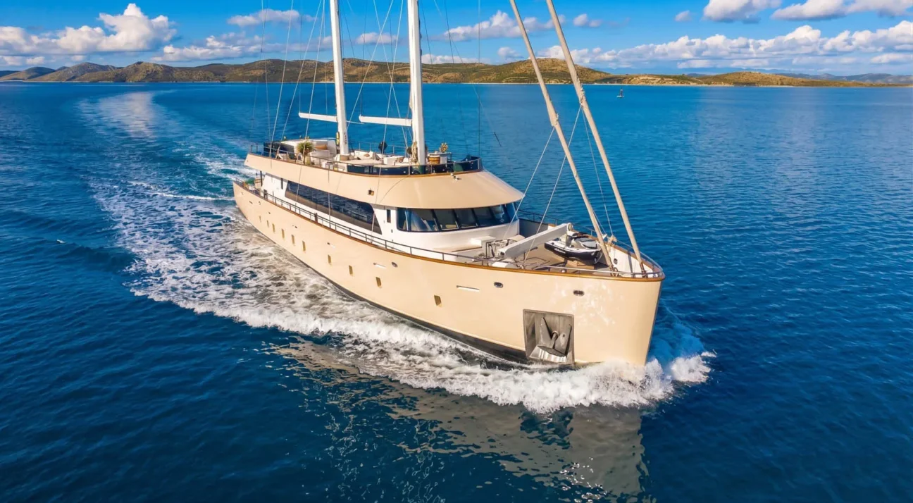 Maxita Luxury Private Yacht Charter Croatia-Luxurious beige motor yacht Maxita cruising in bright blue ocean with a distant island coastline.